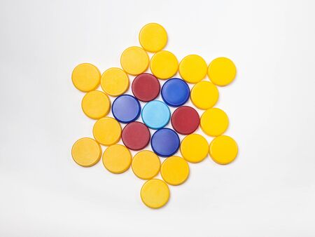 red, blue, yellow, plastic bottle caps are lined up in the shape of a star on a white background.の写真素材