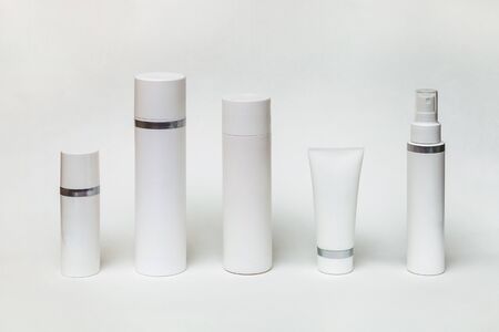 five different white bottles and tubes for cosmetics on a white backgroundの写真素材