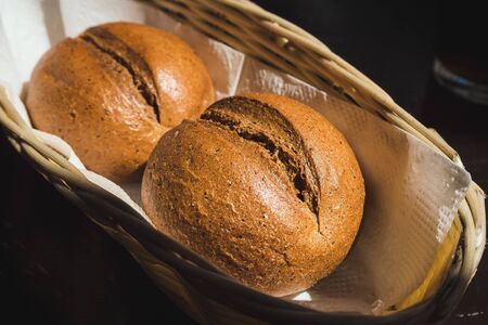 two rye round buns on a napkin in a straw basket close-upの写真素材