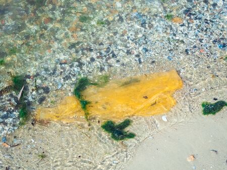 big yellow plastic bag floating in the seaの写真素材