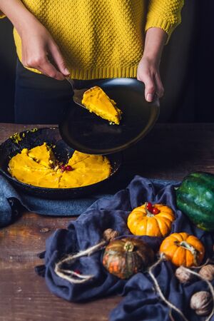 pumpkin pie in a cast iron pan, autumn fruits and vegetables decorated with fabrics on a wooden tableの写真素材