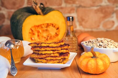 still life: homemade fried pumpkin-oat pancakes on a plate with ingredients close-upの写真素材