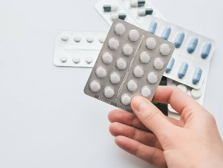20 white tablets in a silver blister in hand close-up. The concept of drug treatment. Copy space for your text on a white background.の写真素材