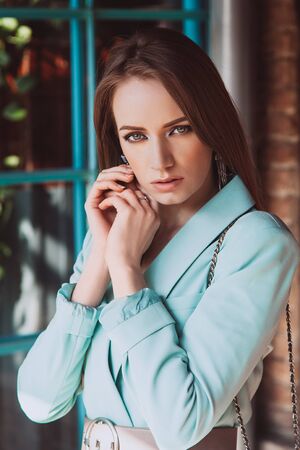 young attractive girl looking at the camera and touching her cheek. Photo session on the street. Skin retouching.の写真素材