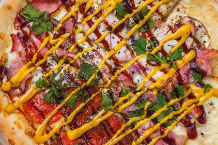 food background - pizza with pepperoni, bacon, boiled pork, mustard and barbecue sauces, seasonings and herbsの写真素材