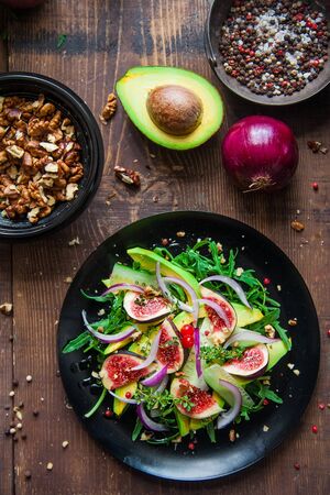 salad on a black matte plate: arugula, figs, avocado, red onions, cucumbers, walnuts, viburnum, thyme, spicesの写真素材