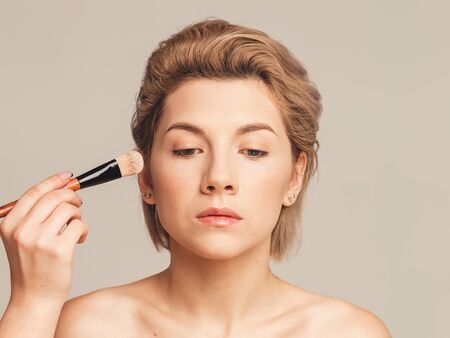 applying foundation on a woman's face. Makeup artist training concept. Without retouchingの写真素材