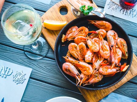 Fried prawns with hot peppers in a frying pan on a wooden board. Table settingの写真素材