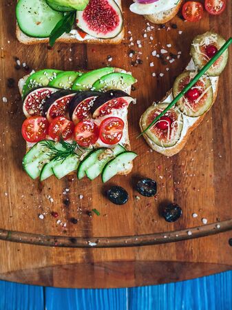 two sandwiches and two bruschettas on a wooden cutting board, top viewの写真素材