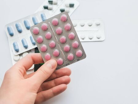 20 pink tablets in a silver blister in hand close-up. The concept of drug treatment. Copy space for your text on a white background.の写真素材