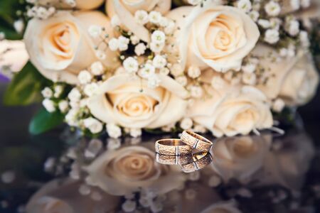 wedding rings and bouquet on black glassの写真素材