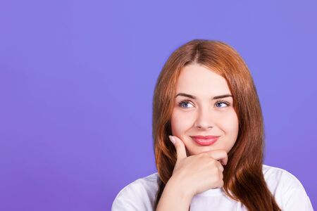 young beautiful red-haired girl looks upwards and smile. Studio shot, close-up, skin retouchの写真素材