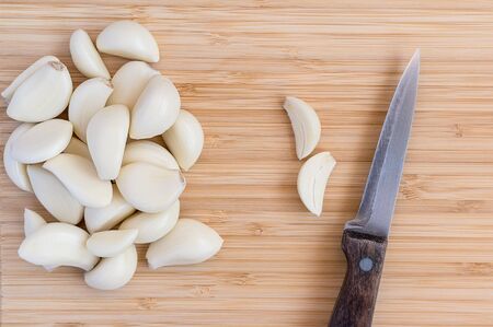garlic head cut in two on a bamboo cutting board, knifeの写真素材