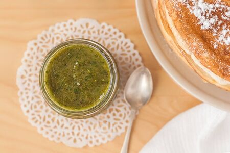 Jar of feijoa jam, pancakes on a plate, silver teaspoonの写真素材