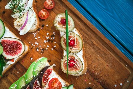 two sandwiches and two bruschetta on a wooden cutting board, top viewの写真素材