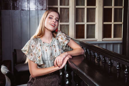 beautiful girl with natural blond hair and blue eyes is sitting at the bar counter and smilingの写真素材