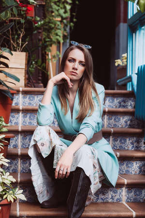 Young beautiful model with blond hair sitting on the stairs. Skin retouching.の写真素材
