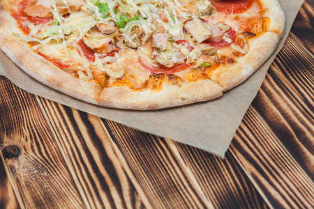 Caesar pizza with lettuce, chicken, soyce, tomatoes, cheese on a wooden tableの写真素材