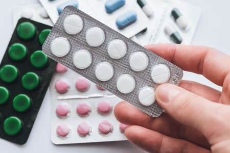 10 tablets in a silver blister in hand on a white background close-up. The concept of medication, treatmentの写真素材