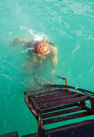 diver in an old diving suit immerses in waterの写真素材