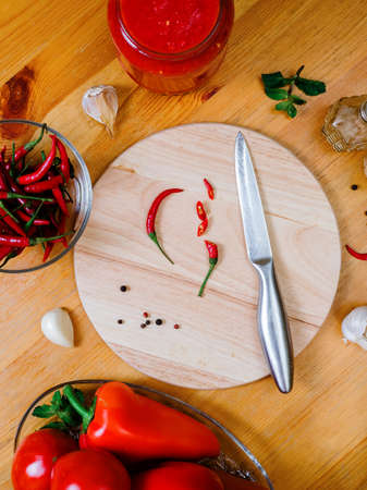 chili sauce preparation: small hot peppers on a round cutting board on a wooden tableの写真素材