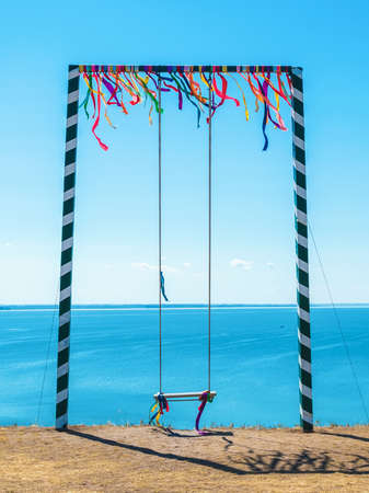high swing decorated with colorful ribbons against the background of the sea - a place for rest and relaxationの写真素材