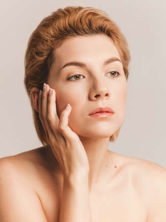 close-up portrait of beautiful blonde woman with short hair on beige background in studioの写真素材