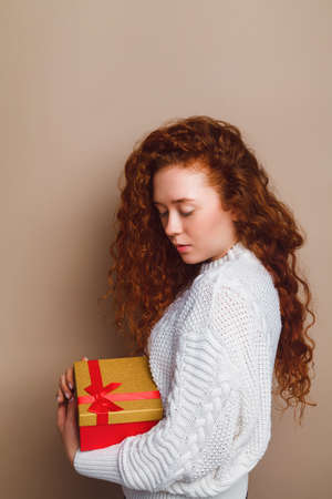beautiful red-haired girl in a white knitted sweater looks at the copy space and smiles cute. Dream conceptの写真素材