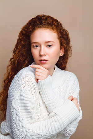 beautiful red-haired girl in a white knitted sweater looks at the copy space and smiles cute. Dream conceptの写真素材