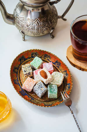 Turkish delight on a vintage plate, Moroccan teapot, honey and tea on a white tableの写真素材