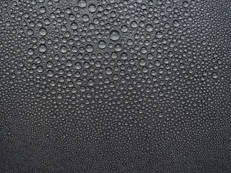 abstract background: many drops of water on a dark surface - non-stick coating in a pan.の写真素材