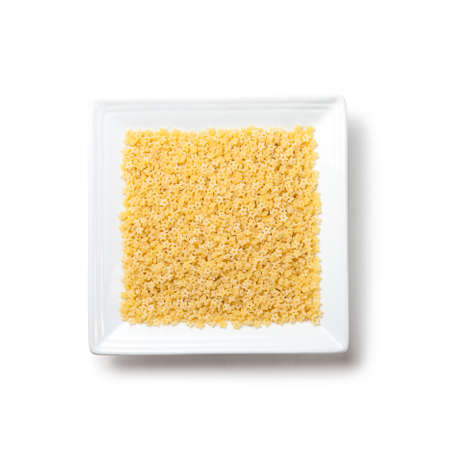 Uncooked pasta stars on white square plate on white background isolatedの写真素材