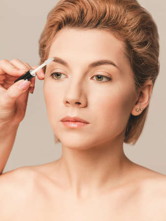 everyday classic makeup in nude color - styling eyebrows with gel. Close-up shot in studioの写真素材
