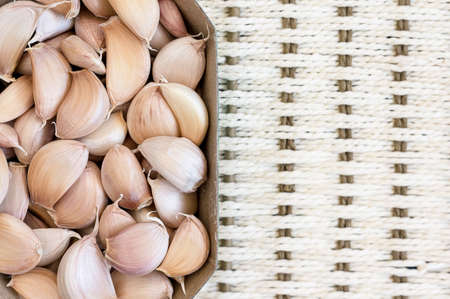unpeeled garlic cloves in a cardboard box on a tableの写真素材