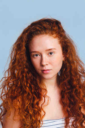 Portrait of a beautiful girl without makeup, no skin retouching. Teen skin care concept. Shot in a studio on a blue background.の写真素材