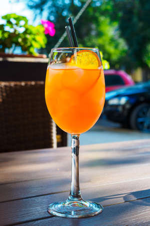 cocktail with a slice of orange on a wooden table on the summer veranda of a cafe in the cityの写真素材