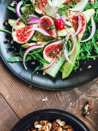 salad on a black matte plate: arugula, figs, avocado, red onions, cucumbers, walnuts, viburnum, thyme, spicesの写真素材