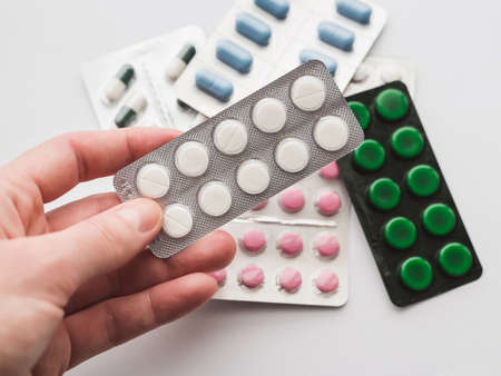 10 tablets in a silver blister in hand on a white background close-up. The concept of medication, treatmentの写真素材