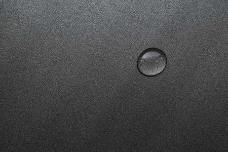 a drop of water on a dark surface close upの写真素材