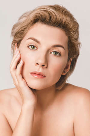short-haired blonde with green eyes looking at the camera. Hand near faceの写真素材