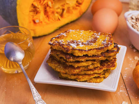 homemade pumpkin pancakes on a square white plate on a background of ingredients close-upの写真素材