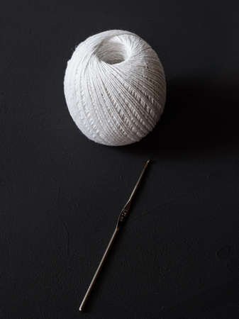 crochet hook and thin white cotton threads on a black background close upの写真素材