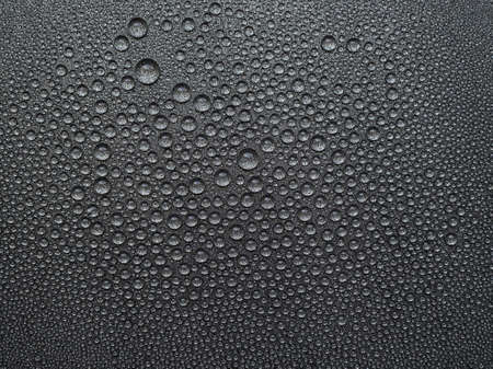 abstract background: many drops of water on a dark surface - non-stick coating in a pan.の写真素材