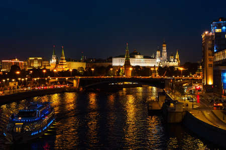 View of the Kremlin and the Moskva River from the Patriarchal Bridge at night, river tram illuminated by lightsの写真素材