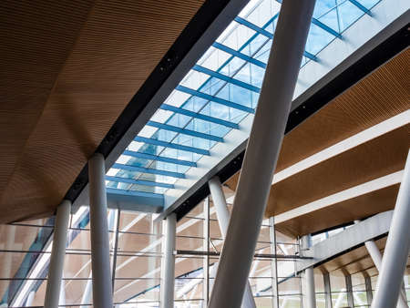 wood-paneled ceiling of a modern building with large glass windows and columnsの写真素材