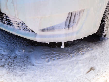 foam dripping from the bumper to the floor at a car wash close-upの写真素材