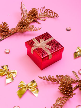 red gift box, golden bows, beads on a pink background - merry christmas and happy new year greetingsの写真素材
