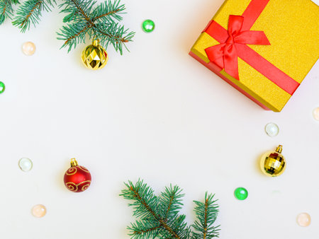 horizontal white Christmas background: two green branches, gold and red Christmas decorations, beads and a gift. Copy space centerの写真素材
