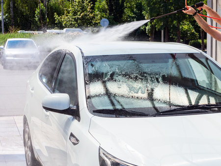 washing the roof of a white car at a self-service car washの写真素材