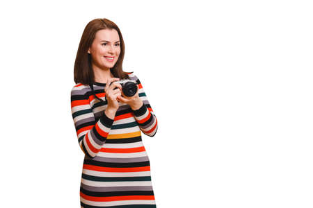 beautiful brown-haired woman in a striped multi-colored dress holds a camera in her hands and...